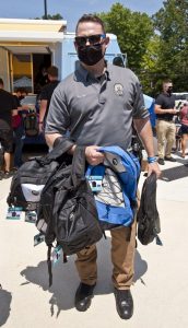 Sgt. Thomas Day holds armfuls of new backpacks